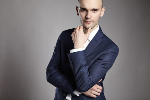 Portrait of young pensive businessman on gray background.