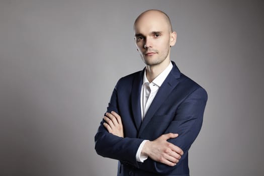 Portrait of young pensive businessman on gray background.