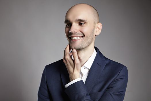 Portrait of a smiling man looking right. He is stroking his chin.