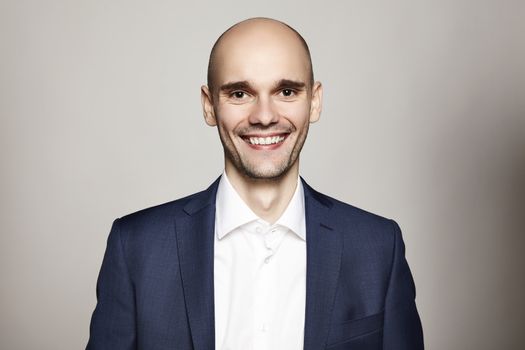 Portrait of young smiling man on gray background.