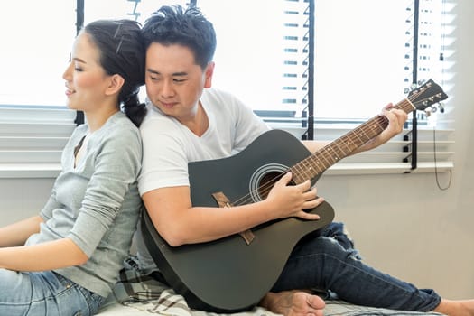 Young Couples playing guitar tohether in bedroom of contemporary house for modern lifestyle concept