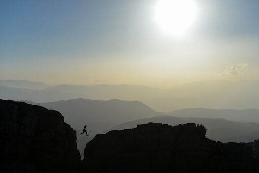 silhouette of the man who jump on the rocks