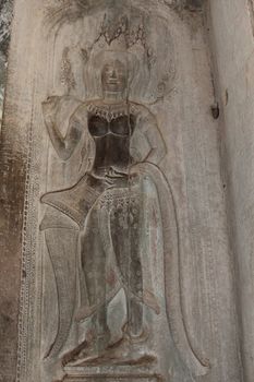 A beautiful ancient relief on the wall of a Cambodian Buddhist temple from Angkor complex, near the antique city of Siem Reap.