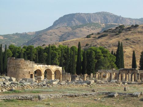 The ruins of an ancient Greek city in the background of hills and green cypresses. Turkey