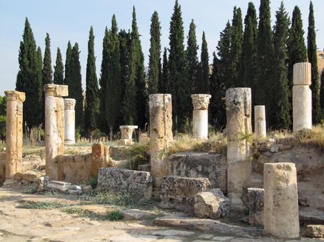 The ruins of an ancient Greek city in the background of hills and green cypresses. Turkey
