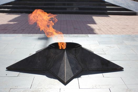 Close image of eternal fire in the form of a star on a marble pedestal