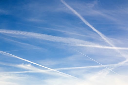 Blue sky with contrails and clouds, for use as background or for copy or text.