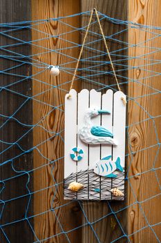 Summer beach style decoration with shells, seagull and fish on weathered wooden background with blue net