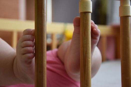 Baby, infant feet sticking out through the rails of a crib, cot, beautiful background for card,  banner, wallpaper design 