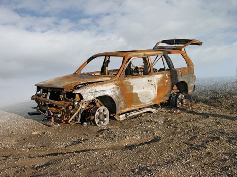 Photo illustration of a burned and rusted out car.