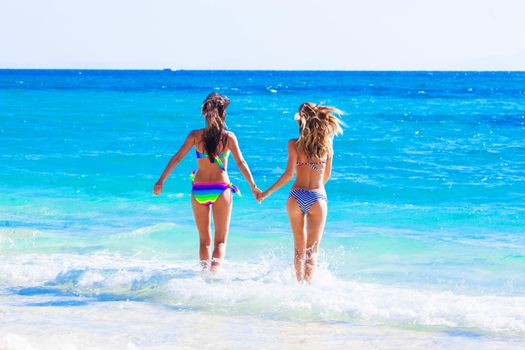 Beautiful happy girls running to tropical sea