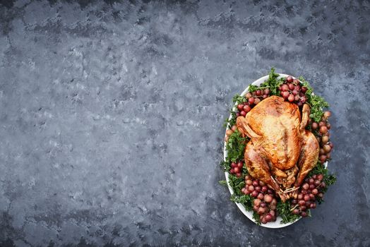 Overhead shot of golden roasted Thanksgiving turkey  on a platter garnished with parsley and fresh grapes against a rustic background. Photo shot in flat lay style. 