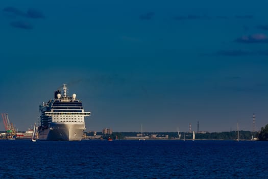 Giant white passenger ship moving past the port on a clear day