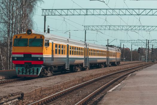 Old yellow passenger diesel train moving at the terminal