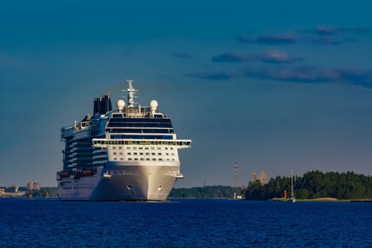 Giant white passenger ship moving past the port on a clear day