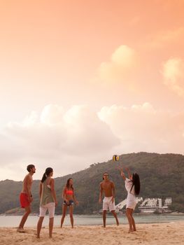 Group of young people playing volleyball at beach