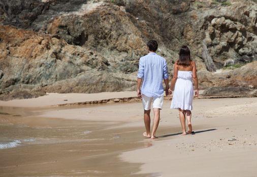 Happy couple walking on sand of tropical beach