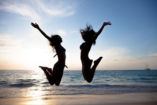 Happy female friends having fun on beach at sunset
