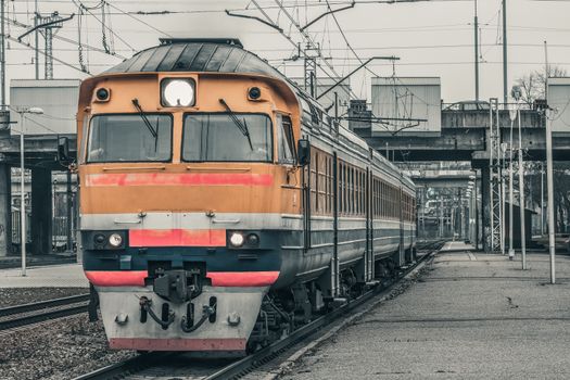 Old yellow passenger diesel train moving at the terminal
