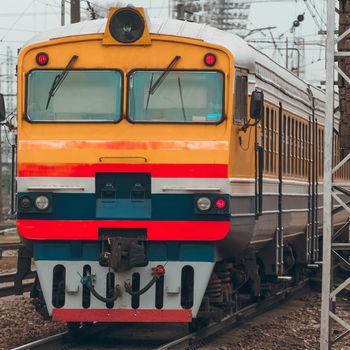 Old yellow passenger diesel train moving at the terminal