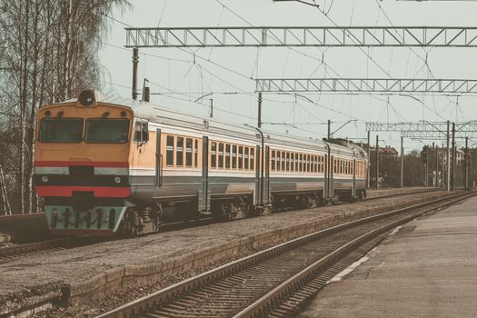 Old yellow passenger diesel train moving at the terminal
