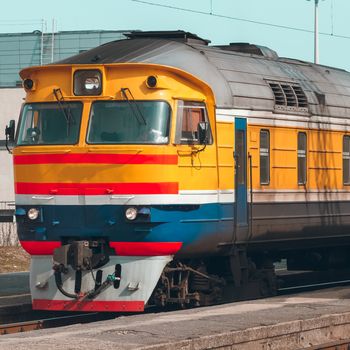 Old yellow passenger diesel train moving at the terminal