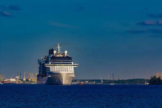 Giant white passenger ship moving past the port on a clear day