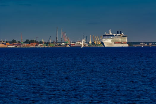 Giant white passenger ship moving past the port on a clear day
