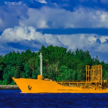 Yellow cargo tanker ship moving at the clear summer day