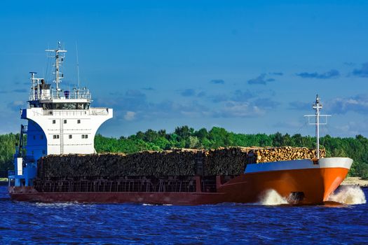 Orange bulk carrier sailing in clear summer day