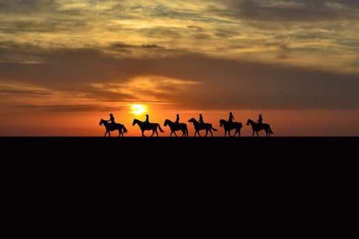 Horse rider silhouettes at sunrise