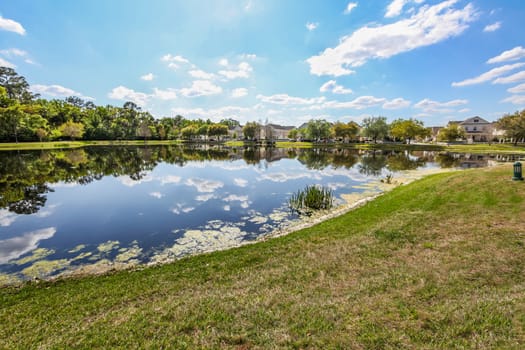 A lake with reflections of sky, trees and houses