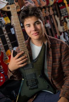 Young man playing the guitar in a shop, France