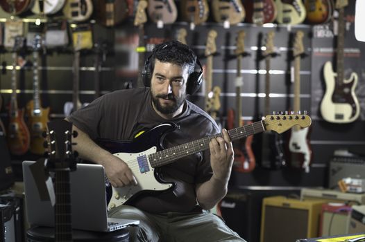 Young man playing the guitar in a shop, France