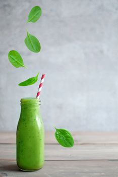 Fresh leafy greens falling into a smoothie bottle with space for text 