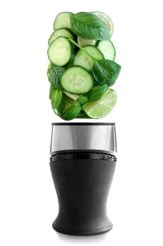 Fresh green fruits and vegetables above a blender on a white background