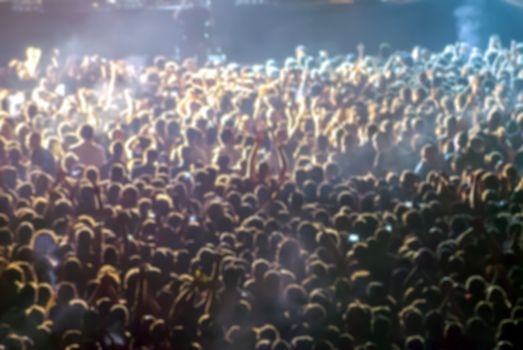 silhouettes of concert crowd in front of bright stage lights. defocused image