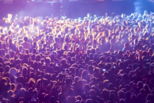 silhouettes of concert crowd in front of bright stage lights. defocused image