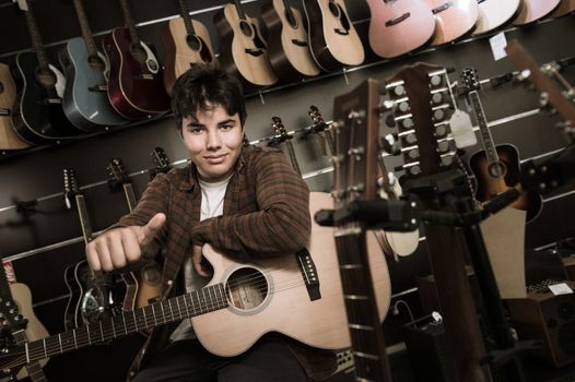 Young man playing the guitar in a shop, France