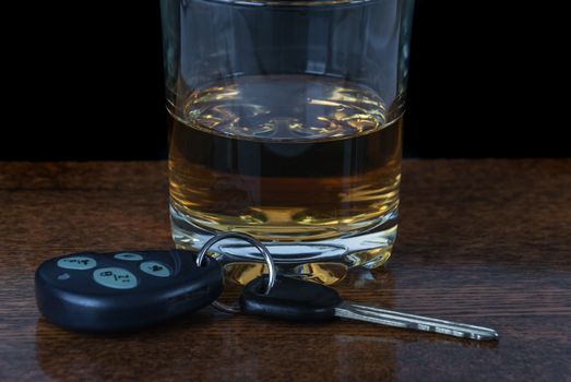 Concept driving and drinking: glass of alcohol and car keys on the bar