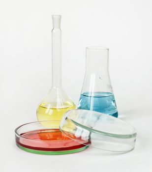 Miscellaneous laboratory glassware with colored solutions on a white background