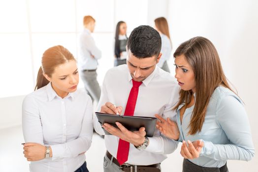 Three young colleagues discussing in front their business team.