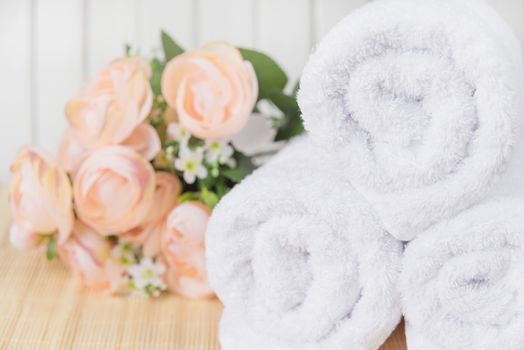 Spa concept: white bath rolled towels and bouquet of pink flowers