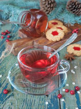 Hot tea in a glass cup, jam and cookies on a background of Christmas decorations