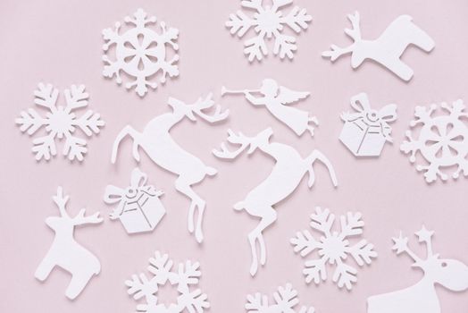 Christmas background composed of white christmas decoration: snowflakes, deers, flying angel and gift boxes on pink background. Christmas wallpaper. Flat lay composition for websites, social media, business owners, magazines,  bloggers, artists etc.