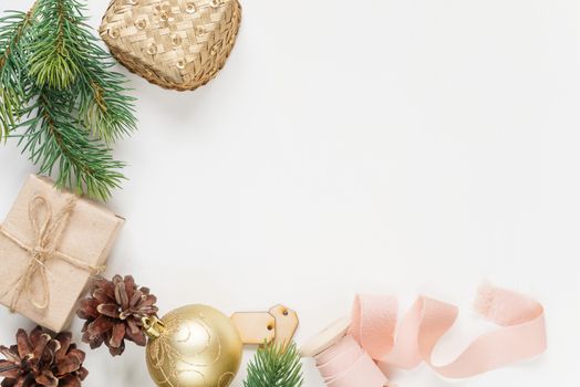 Christmas frame, consisting of fir branches, cones, gift boxes, Christmas golden ball and a pink ribbon on a white background