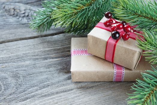 Christmas frame composed of green  branches of spruce, pine cones, gift boxes with holly berries on the background of wooden boards. Flat lay composition for greeting cards, websites, social media, magazines, bloggers, artists etc.