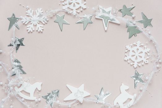 Christmas frame composed of white christmas decoration: snowflakes, stars, Christmas trees and toy; rocking horse on pink background. Flat lay composition for greeting card, websites, social media, magazines,  bloggers, artists etc.