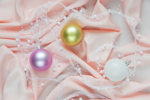 Beautiful Christmas composition with Christmas balls on a pink folded silk. Flat lay composition for greeting cards, websites, social media, magazines, bloggers, artists etc. Christmas wallpaper