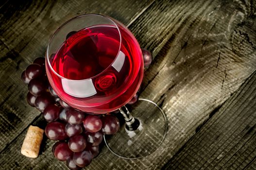 Glass of red wine with grapes on a wooden table